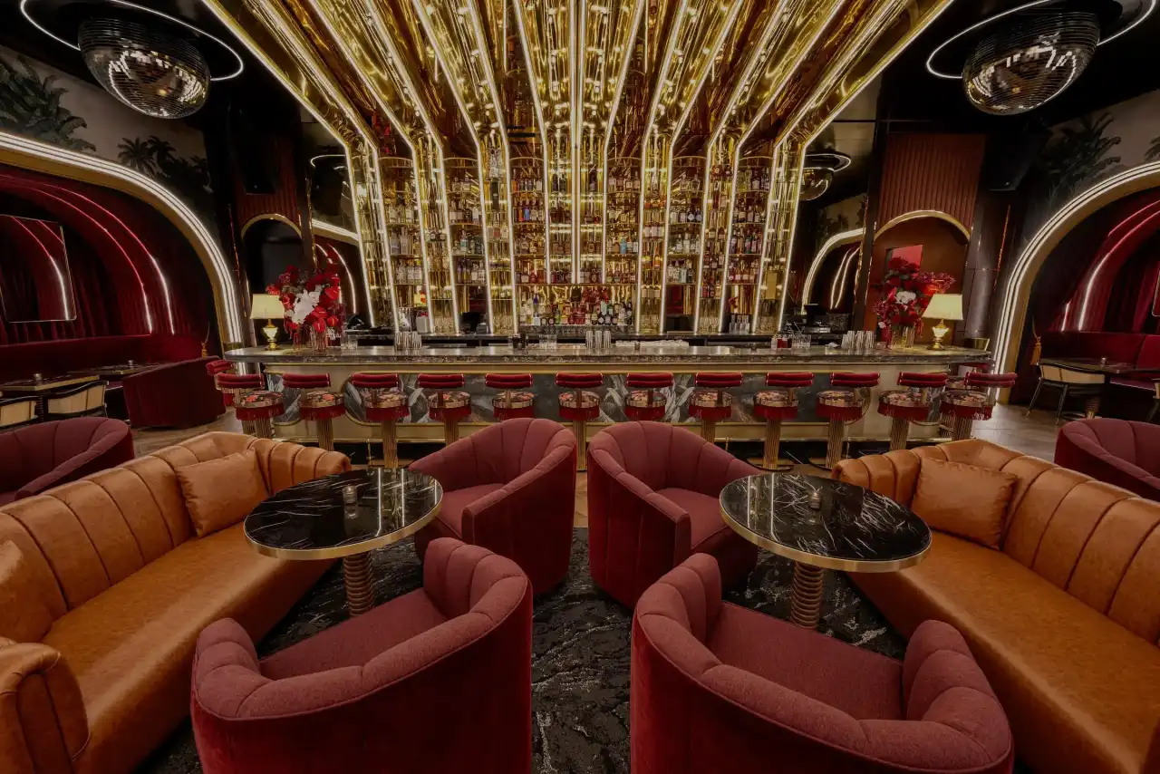 The marble-topped bar with gold shelving and red velvet stools