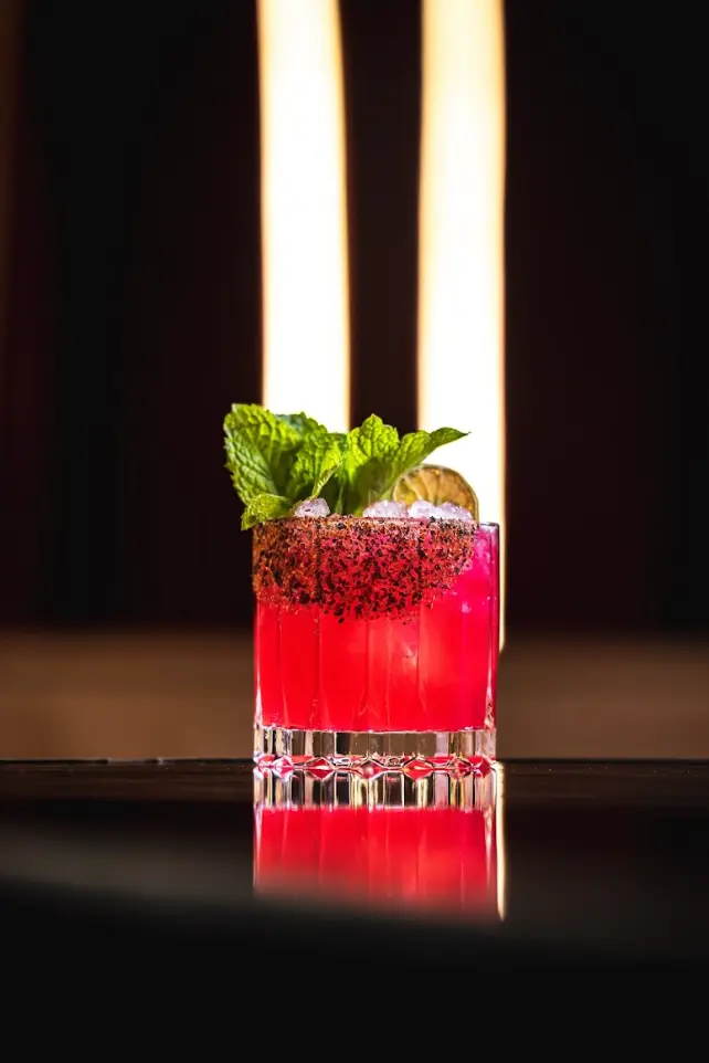 A red cocktail with fresh mint on the bar
